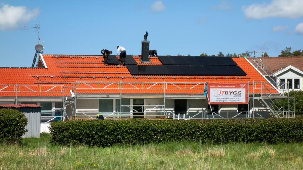 Solar installers fitting roof-mounted solar PV panels on a house
